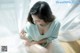 A woman sitting on the floor in front of a white curtain.