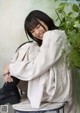 A woman sitting on a chair next to a potted plant.