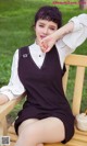 A woman sitting on a wooden bench in a park.