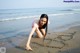 A woman in a pink bikini writing in the sand on the beach.