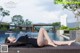 A woman in a black bathing suit laying on a lounge chair by a pool.