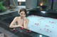 A woman sitting in a bathtub with rose petals on the floor.