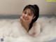 A woman in a bathtub with foam on her face.