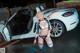 A woman in a bikini standing next to a white car.