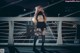 A woman standing on a bridge at night.