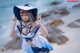 A woman in a sailor outfit posing on the beach.