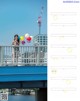 A woman standing on a bridge holding a bunch of balloons.