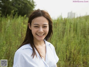 A woman standing in a field of tall grass smiling.