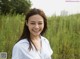 A woman standing in a field of tall grass smiling.