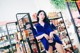 A woman in a blue shirt and black panties standing in front of a shelf of food.