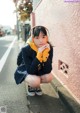 A young woman wearing headphones crouching down on the street.