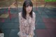 A young woman sitting on a swing in a park.