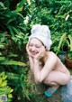 A naked woman with a towel on her head sitting on a rock.